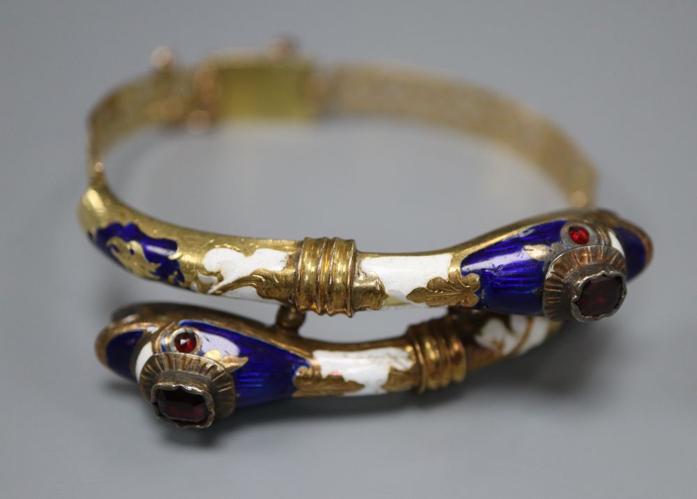 A Victorian pierced yellow metal, two colour enamel and garnet set twin serpent head hinged bracelet, gross 22.5 grams (a.f.).